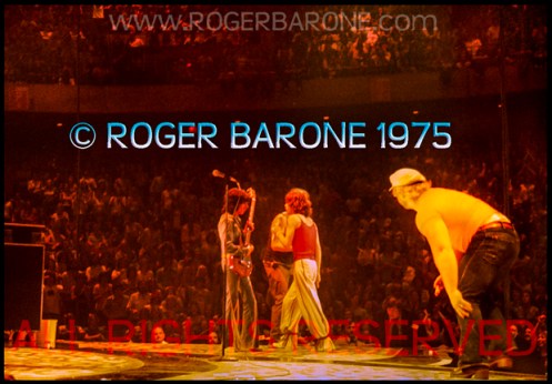 Rolling Stones' security member, Bob Bender, pursues a fan who leaped on stage near Jagger (6/29/75) © roger barone 1975